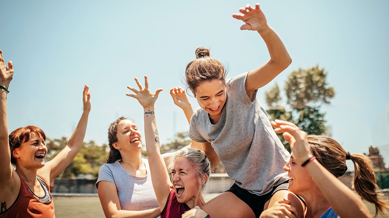 Jubelnde Frauen eines lokalen Sportvereins feiern gemeinsam ihren Erfolg auf dem Spielfeld.
