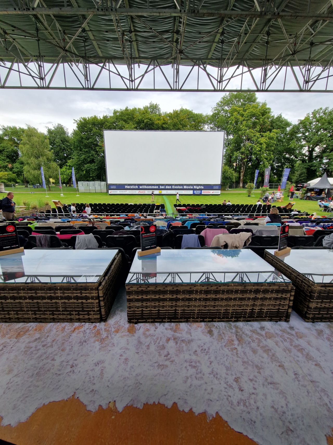 Grosser Aussenbereich mit überdachter Tribüne und Leinwand für eine Filmvorführung im Freien.