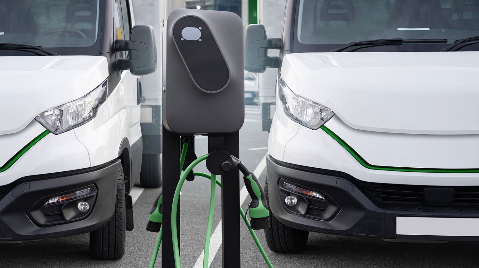 Zwei Elektro-Transporter an Ladestation.