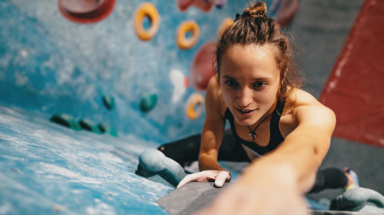 Frau konzentriert sich beim Klettern an der Boulderwand – voller Energie und Zielstrebigkeit.