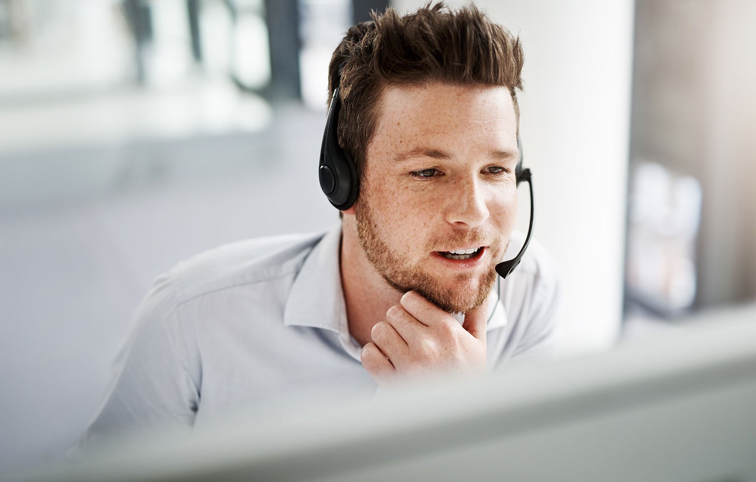 Mitarbeiter mit Headset im Kundengespräch am Bildschirm.