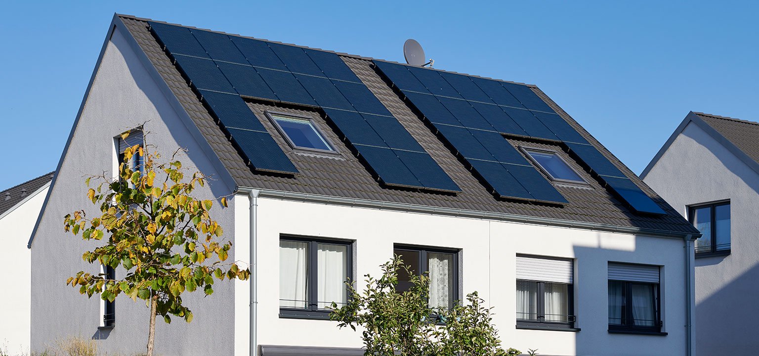 Haus mit Solarpanels auf dem Dach bei Sonnenschein.