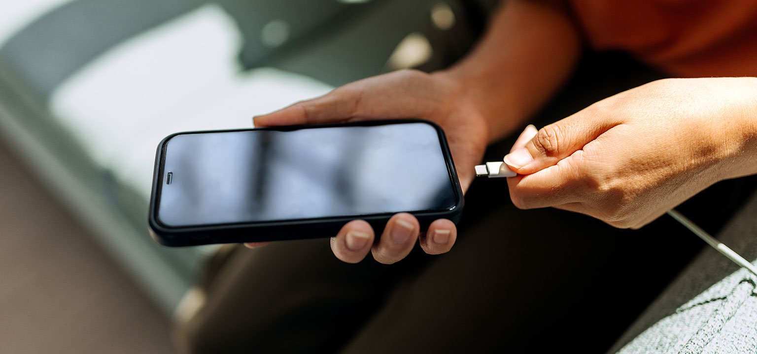 Person lädt ein Smartphone mit einem Ladekabel.