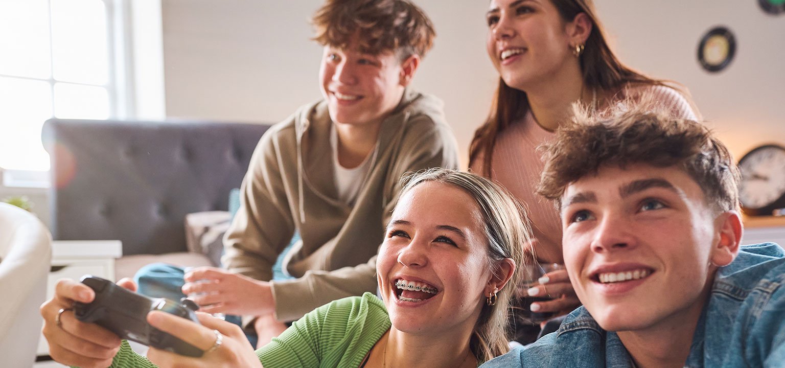 Vier Jugendliche spielen gemeinsam Videospiele und haben sichtlich Spass.