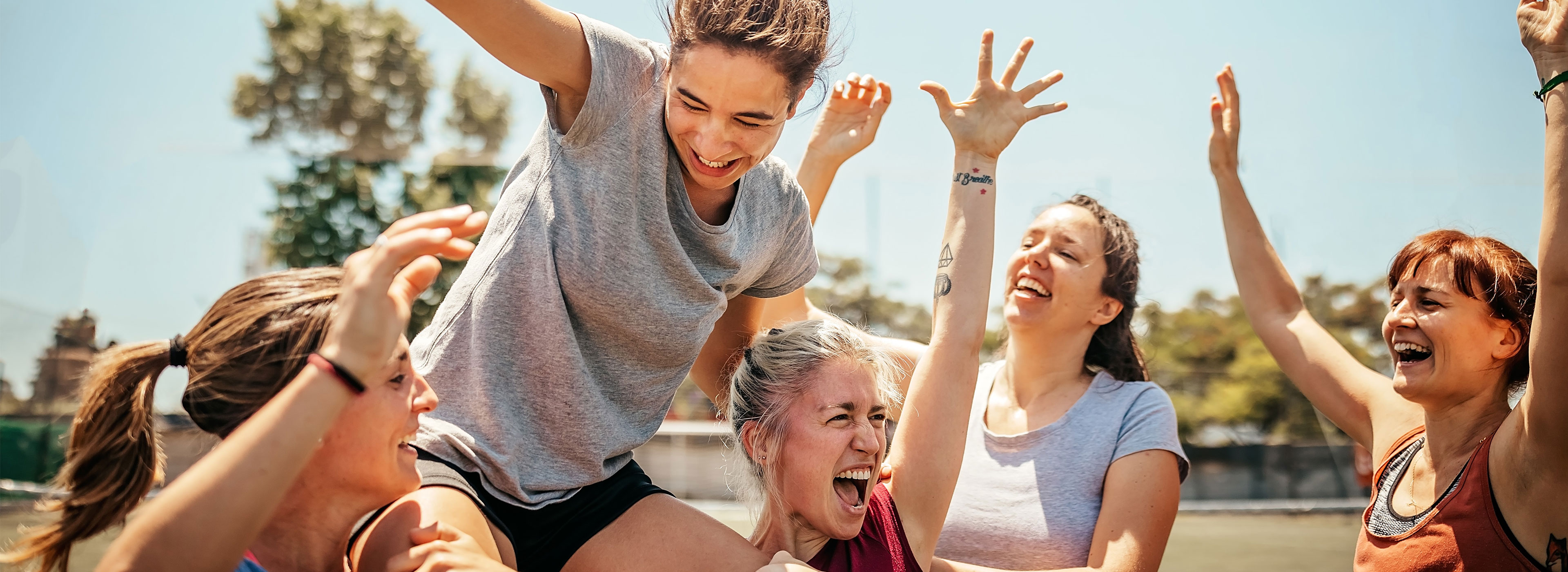 Jubelnde Frauen eines lokalen Sportvereins feiern gemeinsam ihren Erfolg auf dem Spielfeld.