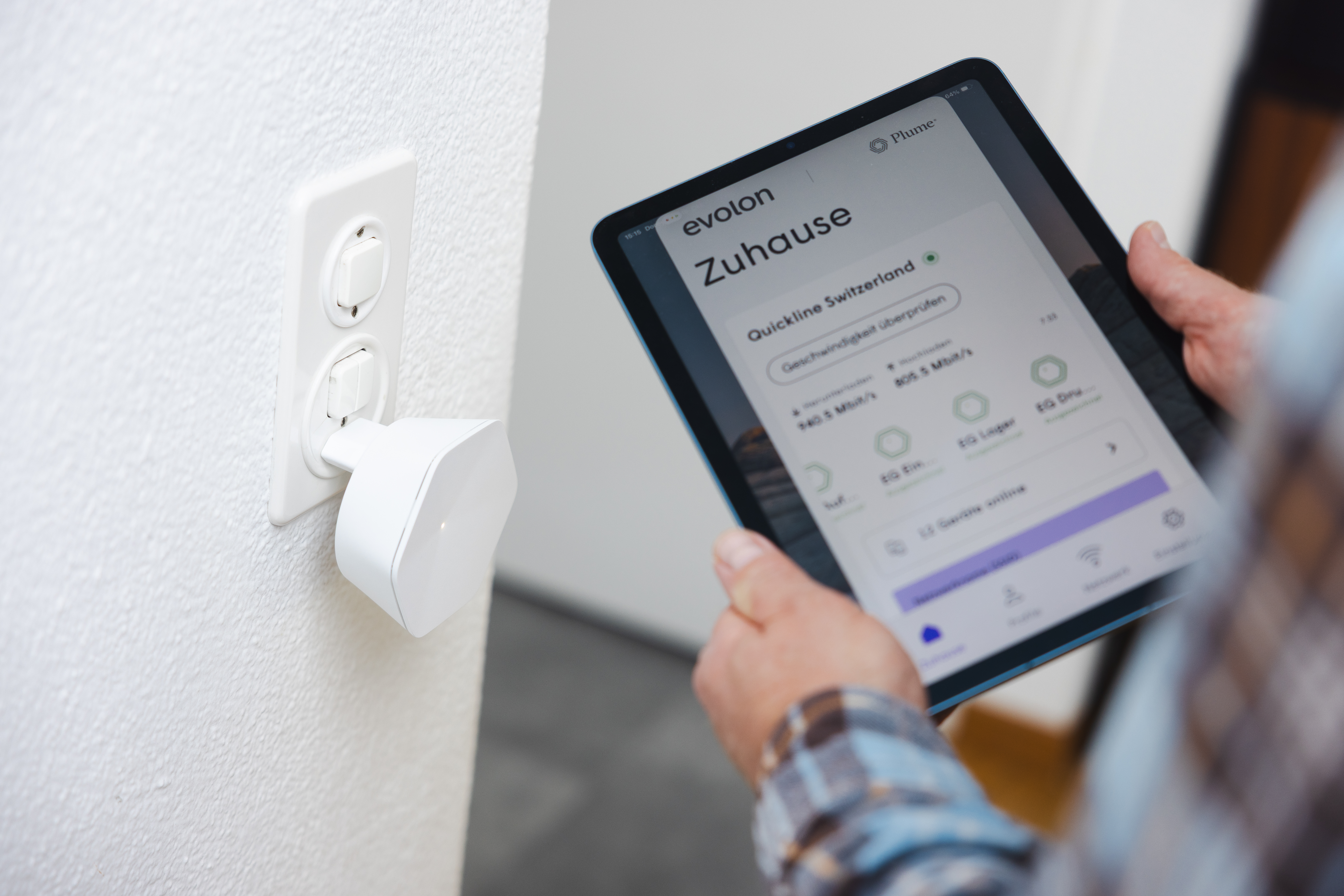 Person nutzt Tablet zur WLAN-Steuerung neben installiertem Mesh-SuperPod an der Wand.