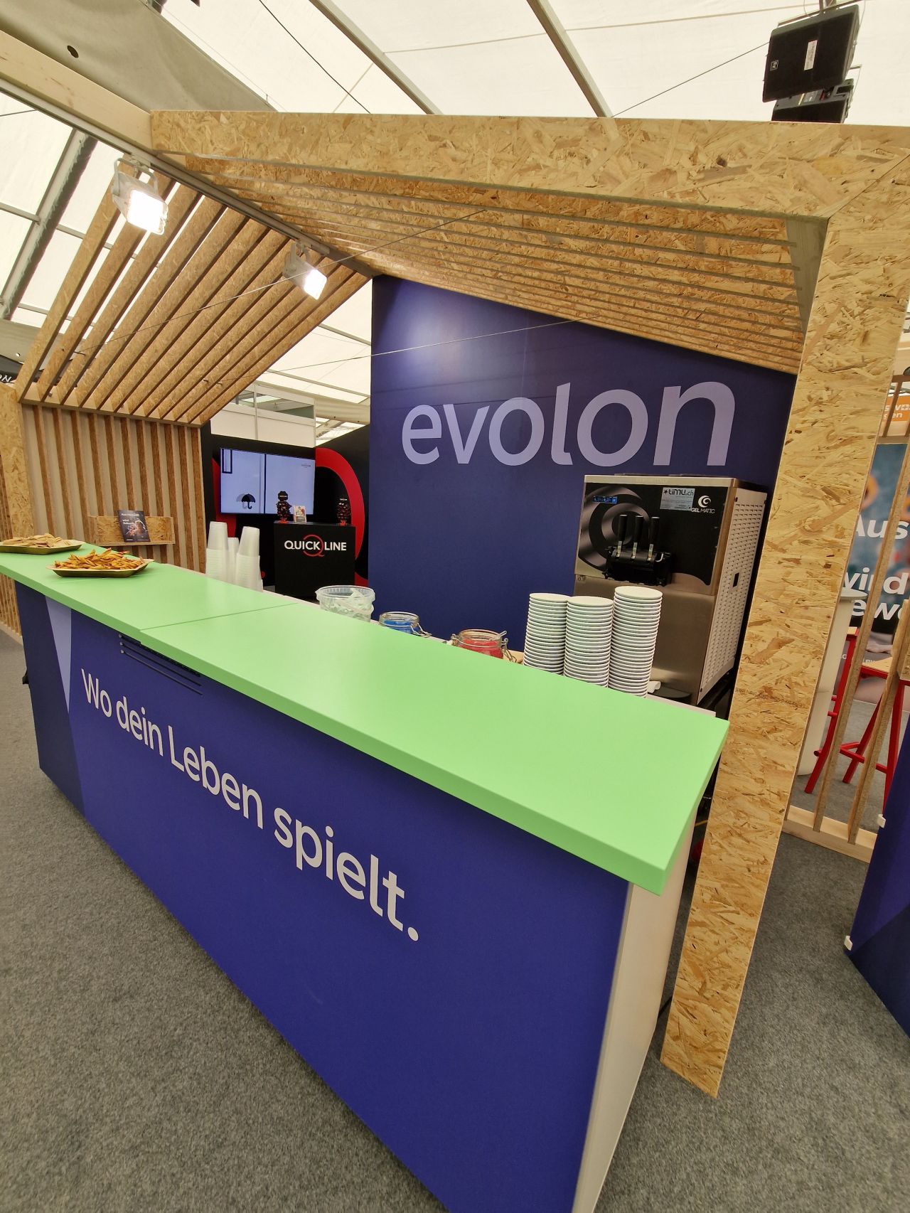 Messestand der Evolon AG mit Glacémaschine und dem Schriftzug «Wo dein Leben spielt.».
