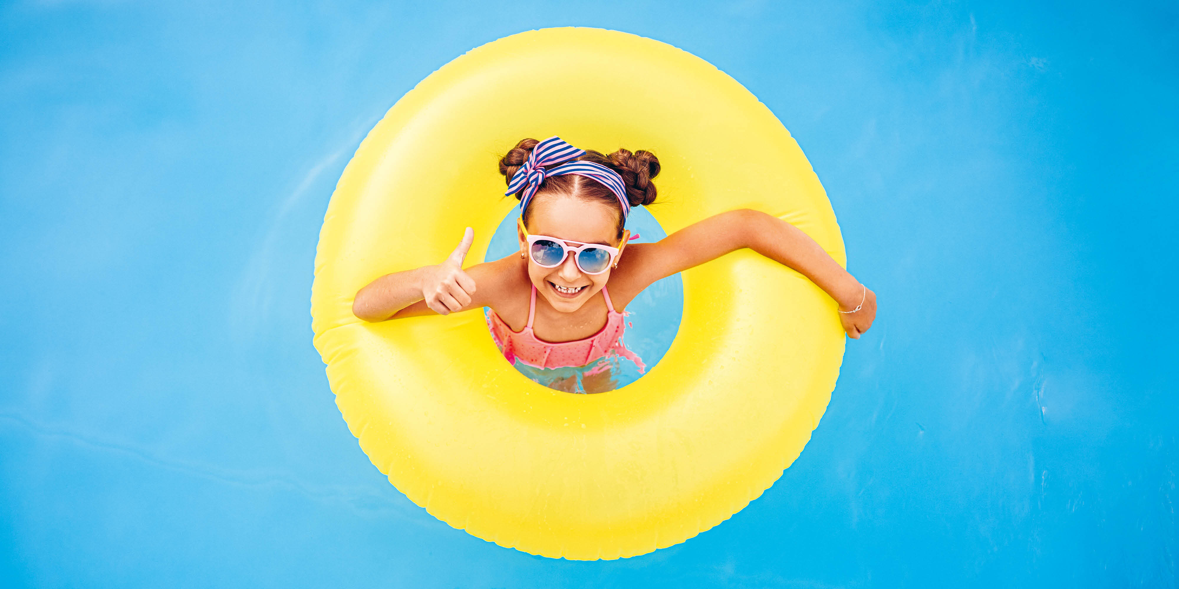 Kind mit Schwimmring im Wasser (Coverbild des Kundenmagazins Flow 1-26)
