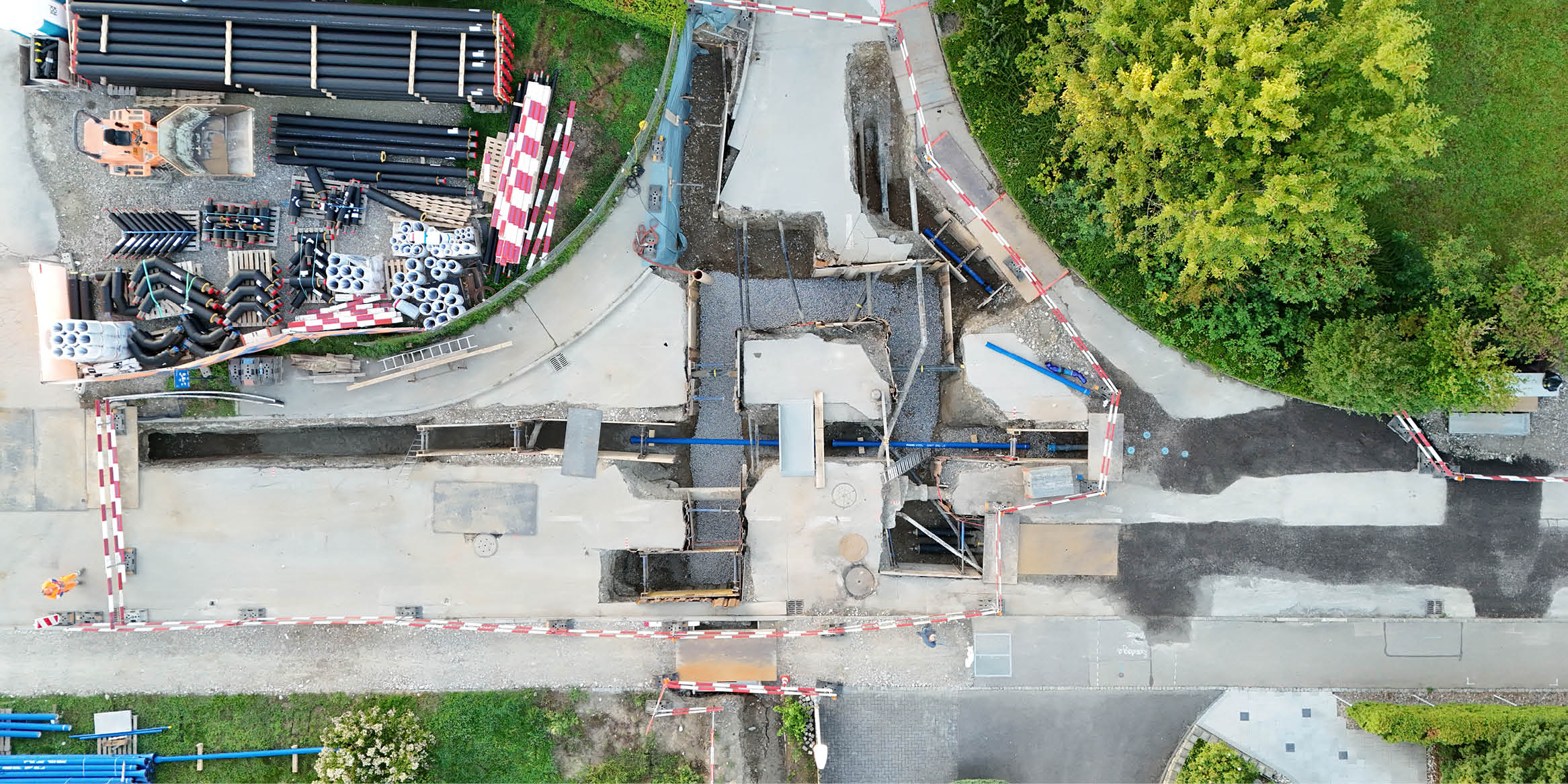 Luftaufnahme einer Baustelle mit offenem Graben für Fernwärmeleitungen.
