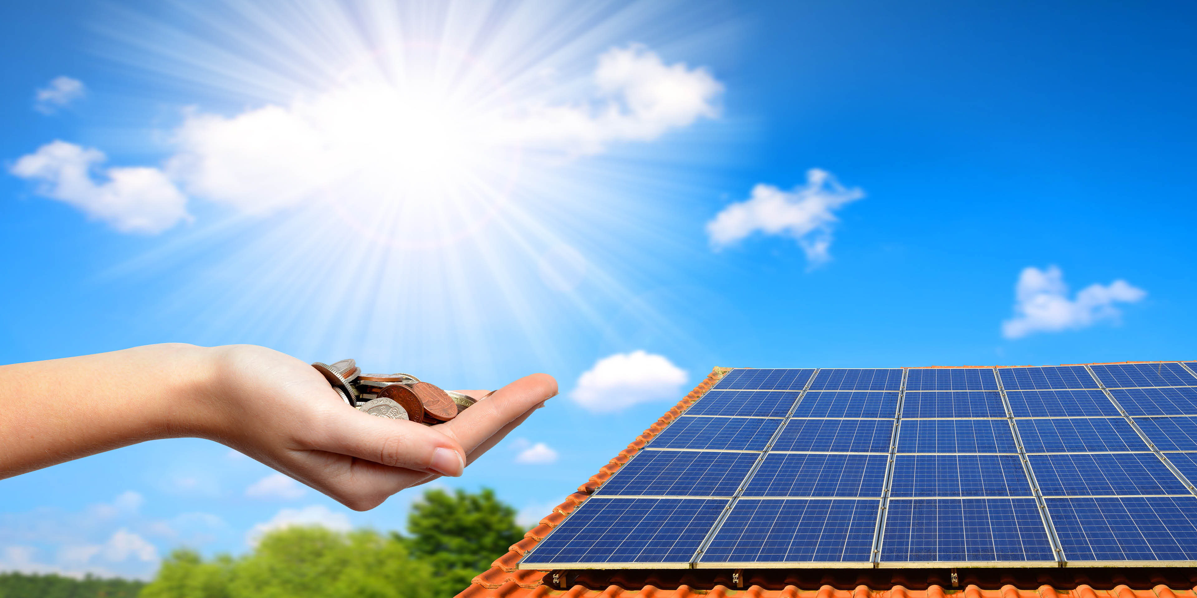 Sonniger Himmel über Photovoltaikanlage auf einem Dach; eine Hand hält Münzen ins Licht als Symbol für Ersparnisse.