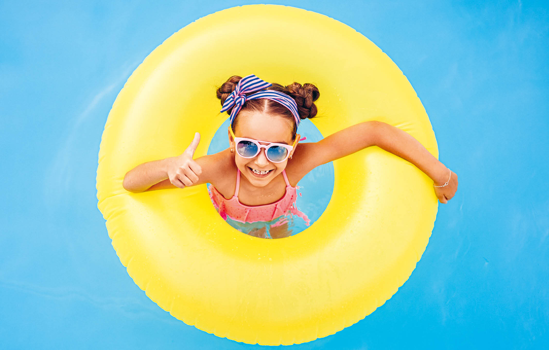 Kind mit Schwimmring im Wasser.