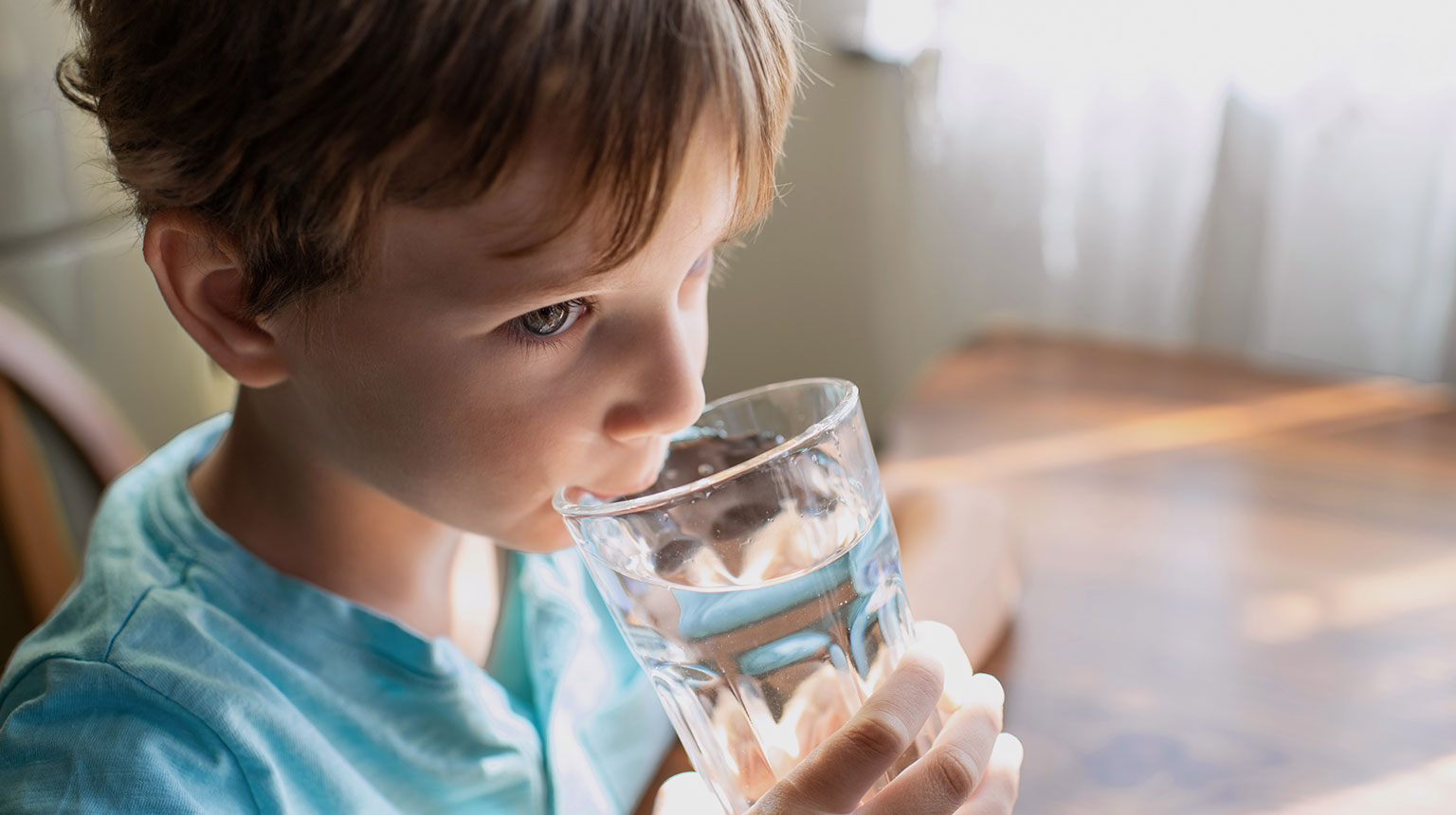 Kind trinkt Wasser aus einem Glas.