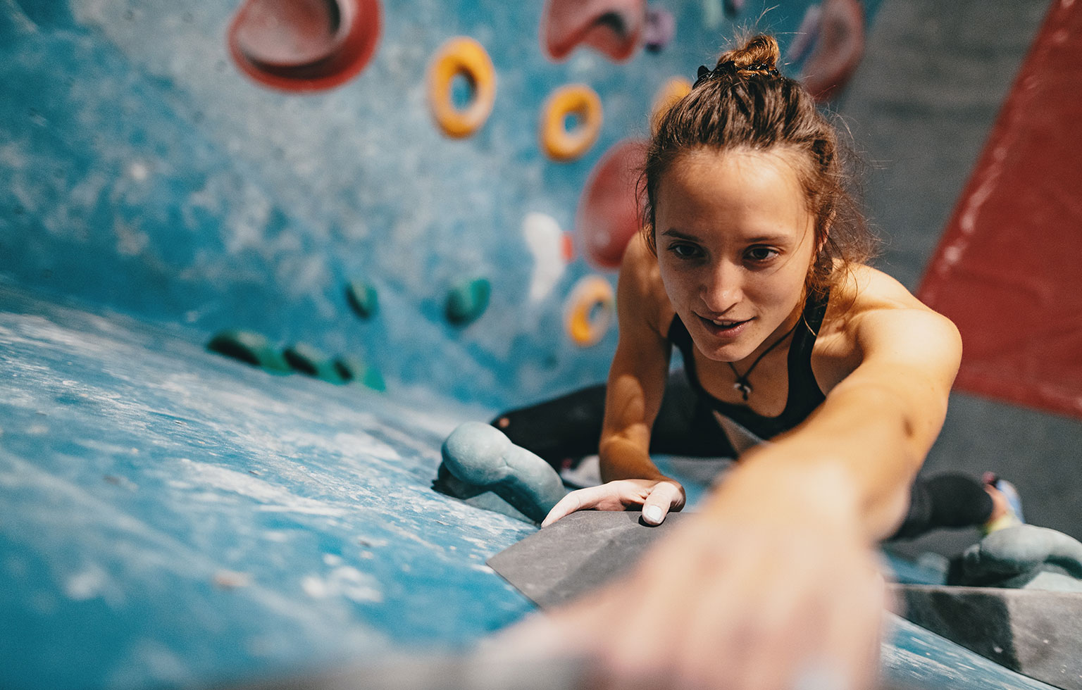 Frau konzentriert sich beim Klettern an der Boulderwand – voller Energie und Zielstrebigkeit.