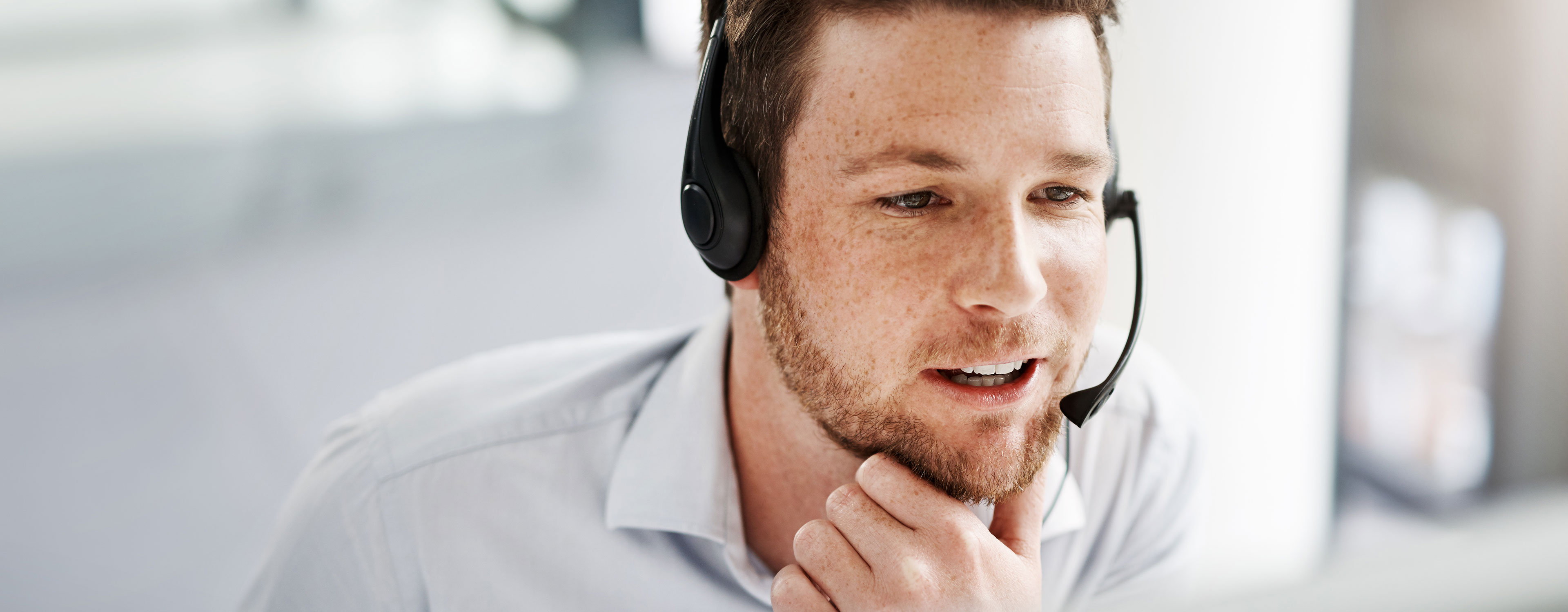 Mitarbeiter mit Headset im Kundengespräch am Bildschirm.