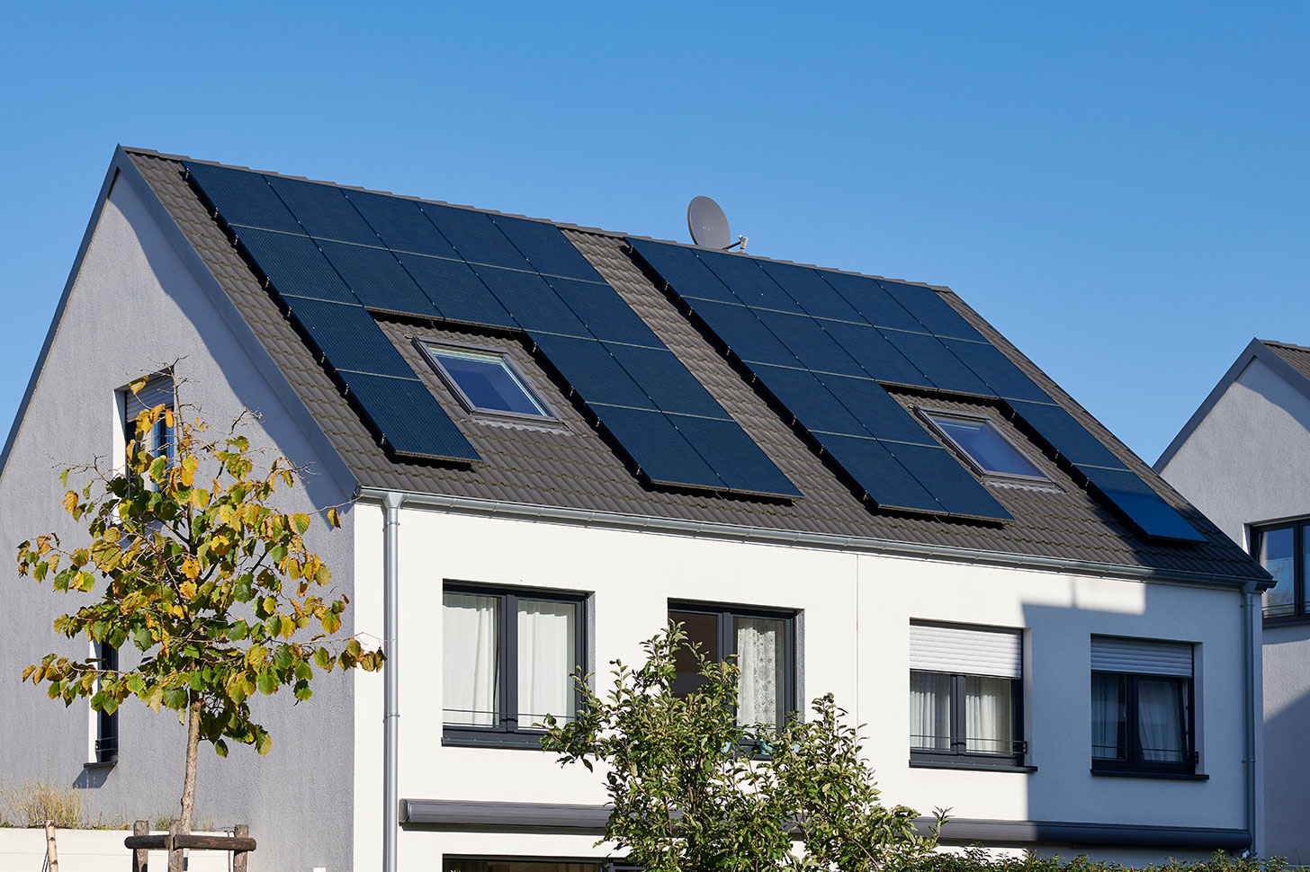 Haus mit Solarpanels auf dem Dach bei Sonnenschein.