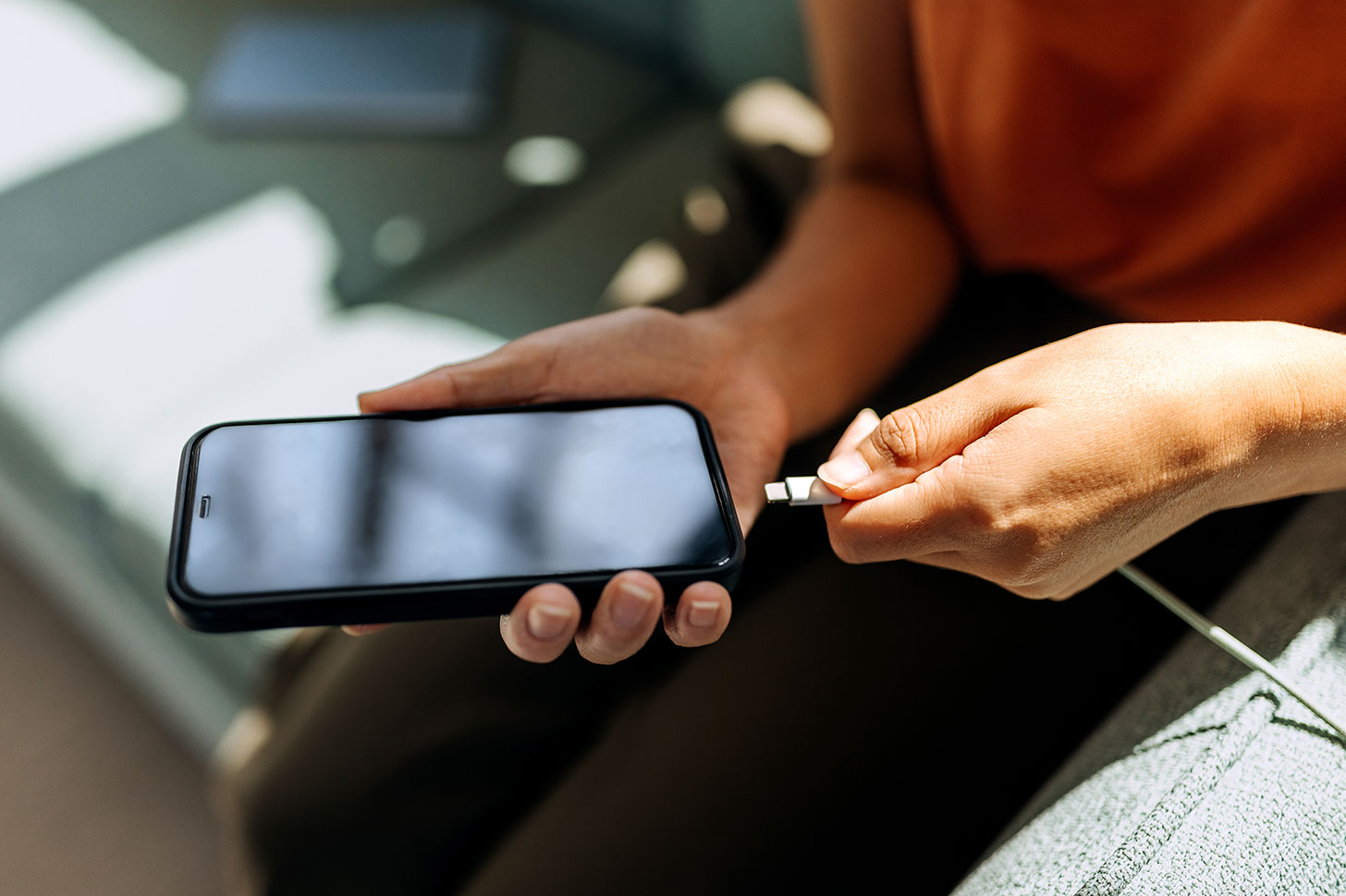 Person lädt ein Smartphone mit einem Ladekabel.
