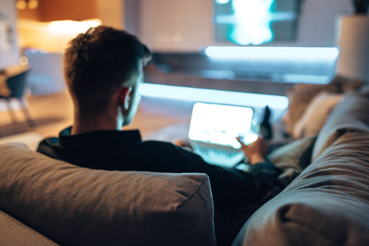 Ein Mann sitzt entspannt auf dem Sofa und nutzt ein Tablet.