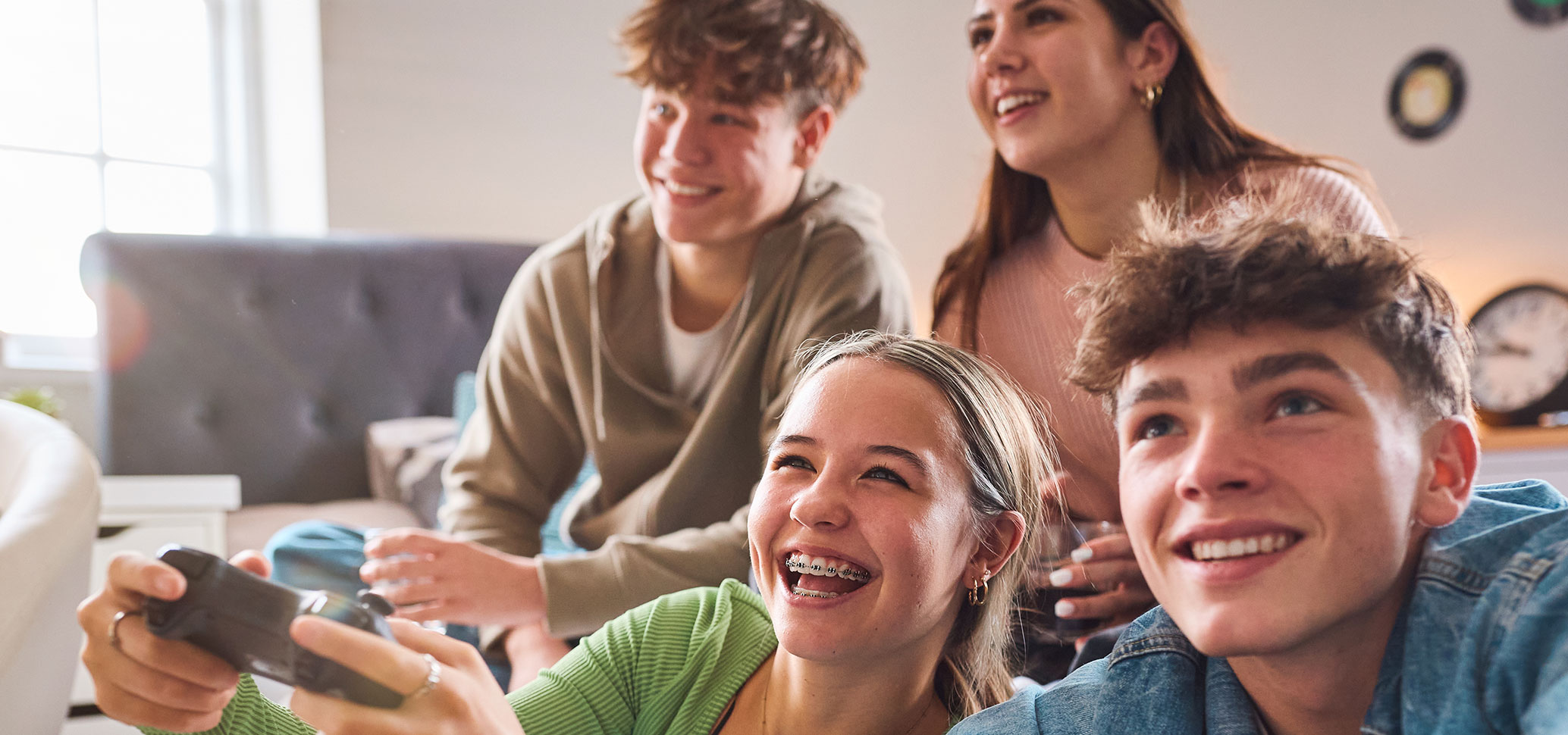 Vier Jugendliche spielen gemeinsam Videospiele und haben sichtlich Spass.