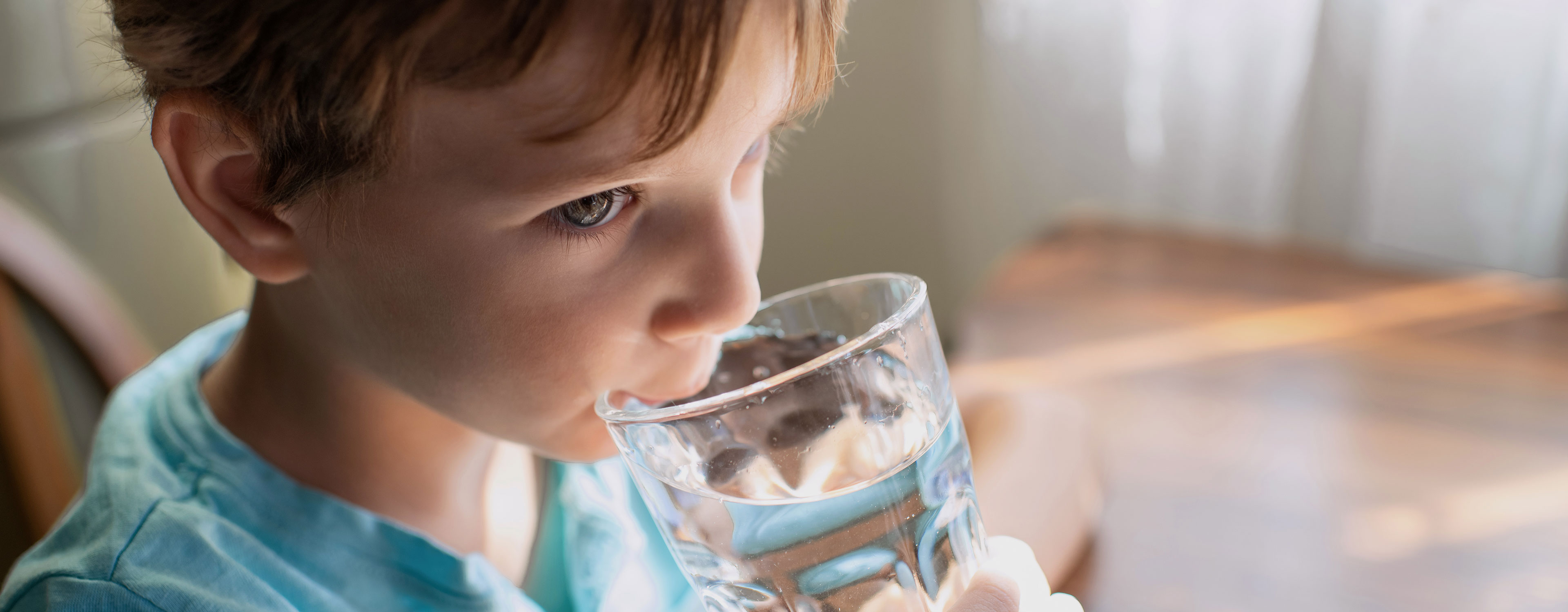 Ein Junge trinkt ein Glas Wasser.